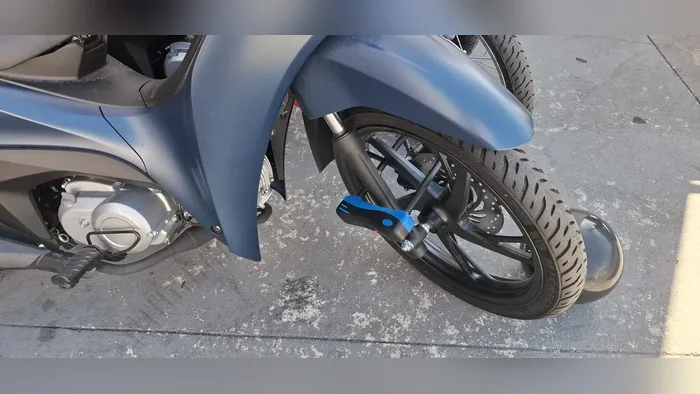 Cadeado em U travando a roda dianteira de uma moto azul
