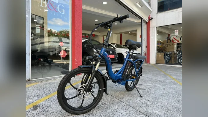 Shineray E-bike azul em vista de três quartos, com a roda dianteira em primeiro plano