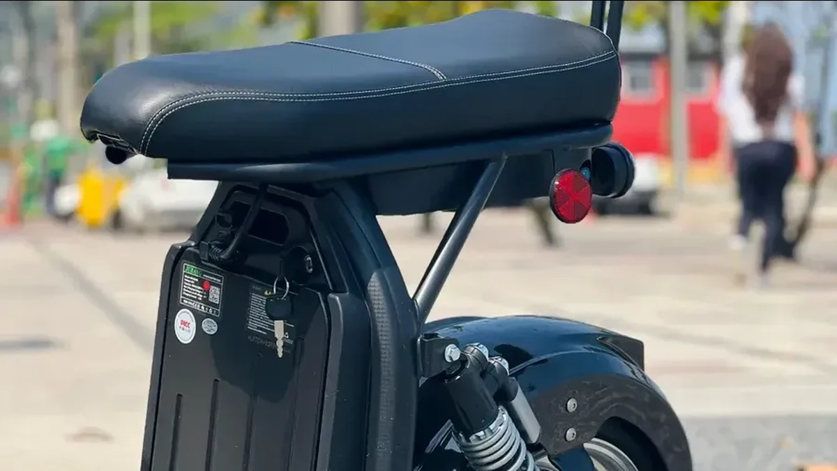 Banco acolchoado, encosto e compartimento da bateria removível de uma scooter elétrica de 3000W numa calçada, imagem ilustrativa de bateria removível