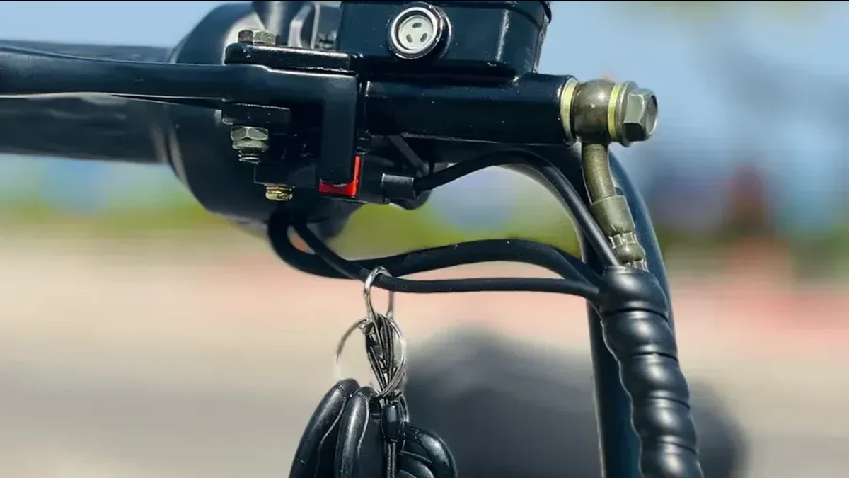 Guidão da scooter X11 3000W com o cartão de acionamento por NFC pendurado ao lado do acelerador