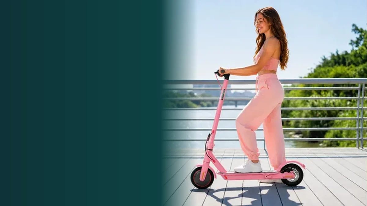 Mulher em pé sobre scooter elétrica rosa em um deque, exemplo de scooter elétrica sem CNH que declara 25 km/h