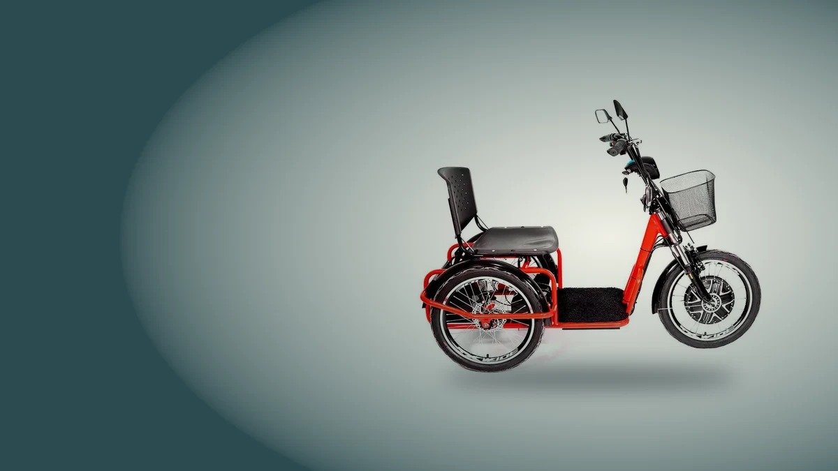 Triciclo elétrico adulto vermelho Village Pam de lado, com cesta, banco com encosto e roda dianteira com motor, sobre fundo cinza azulado